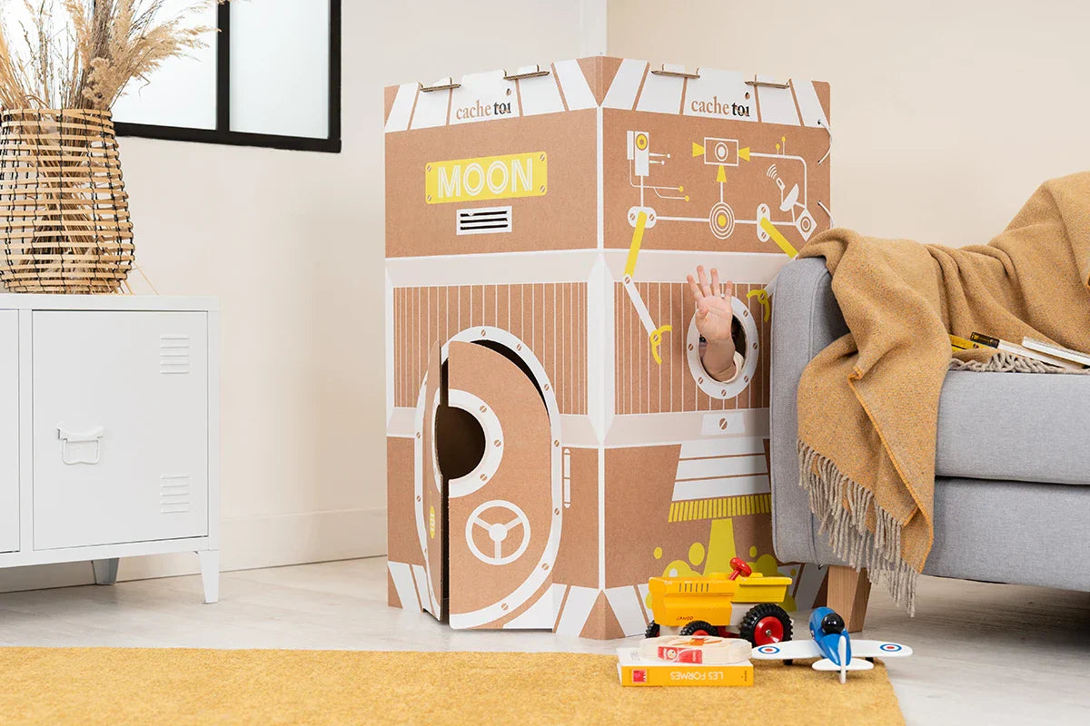 Cabane pliable en carton Moon de la marque cache-toi dans un salon chaleureux.