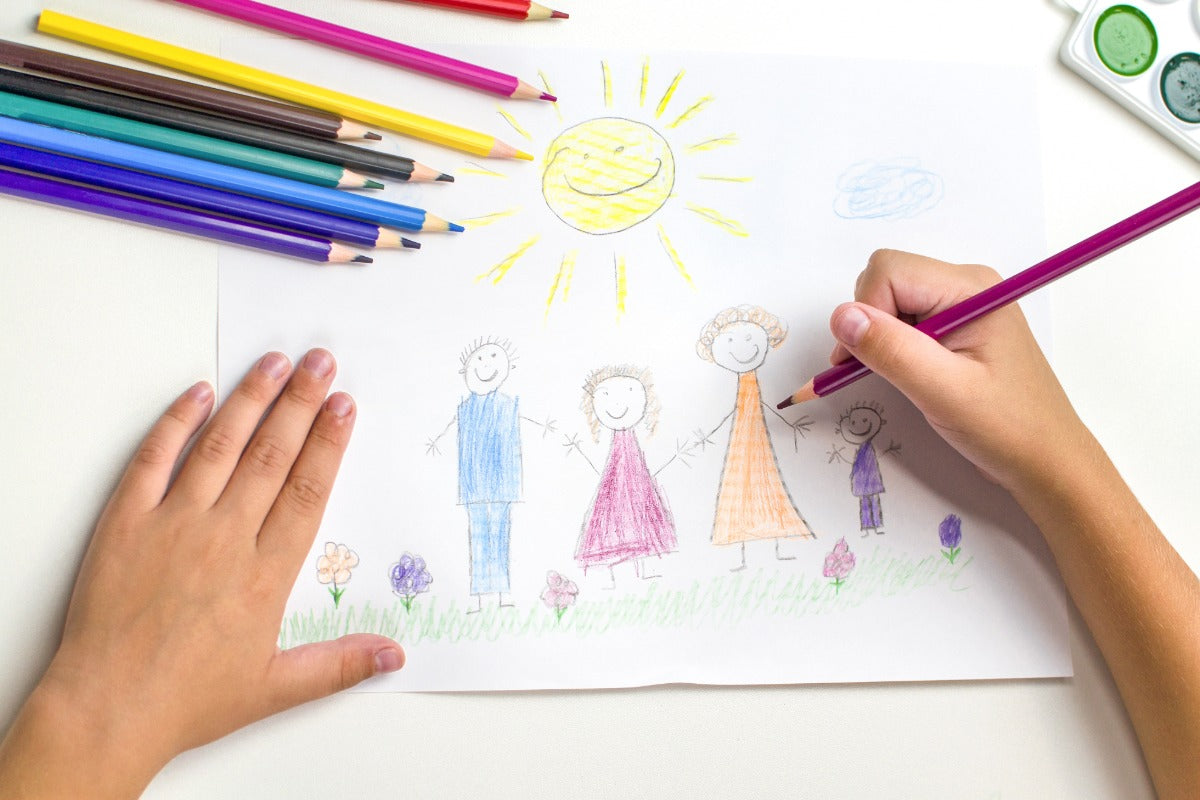 Enfant en train de dessiner une famille avec des crayons de couleur, activité créative à la maison favorisant l’imagination.