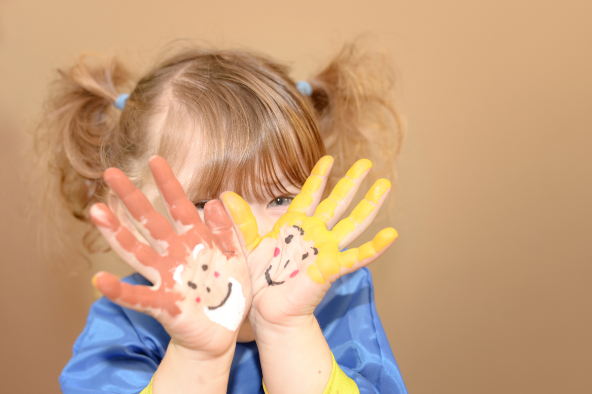 Enfant montrant ses mains peintes lors d’une activité créative de peinture à la maison